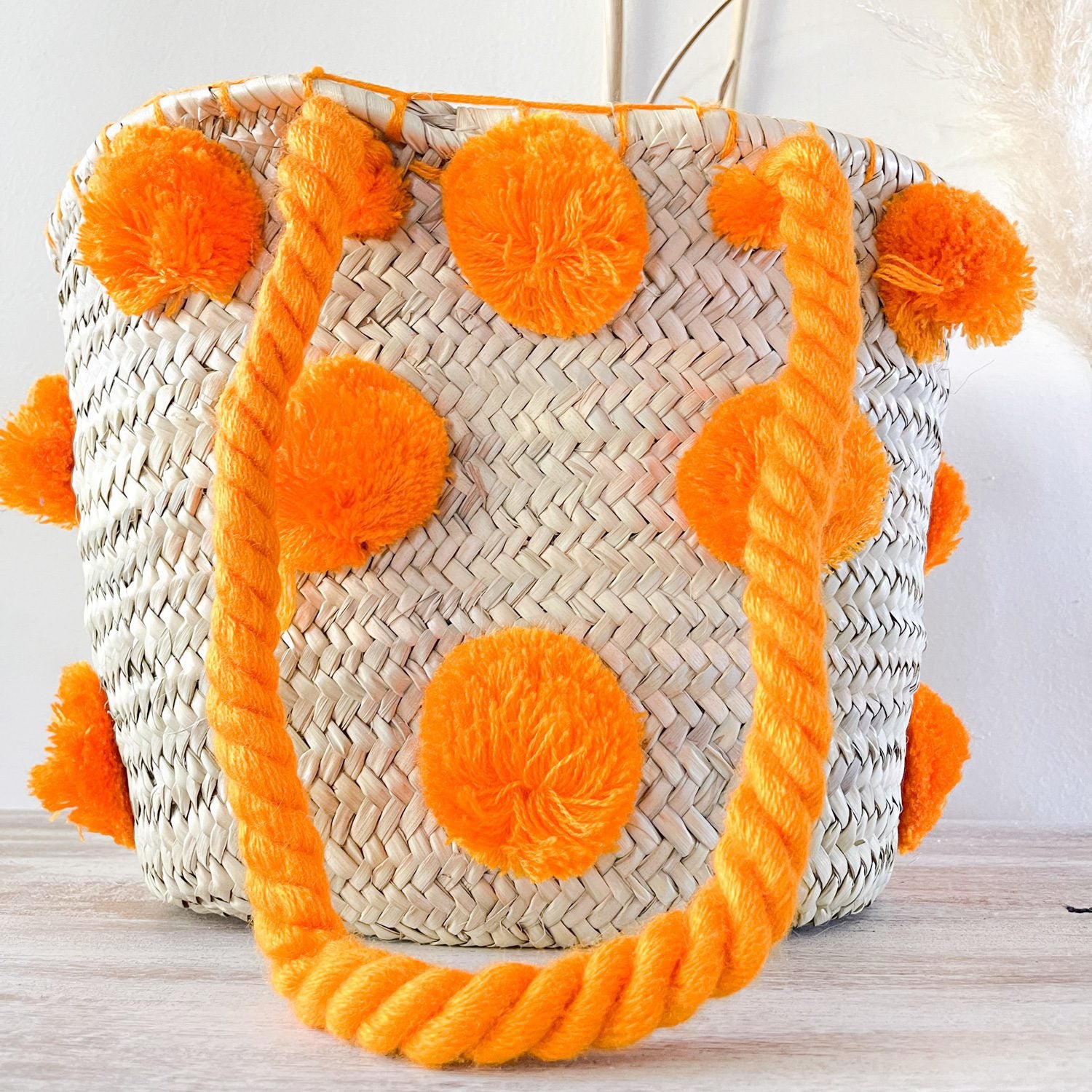 bolso cesta de doum con pompones anaranjados
