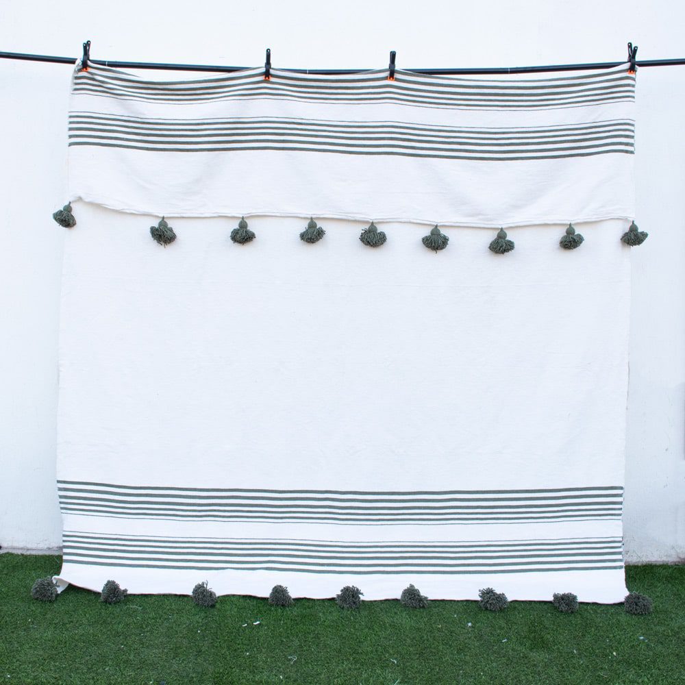 Manta blanca con lineas y pompones verdes