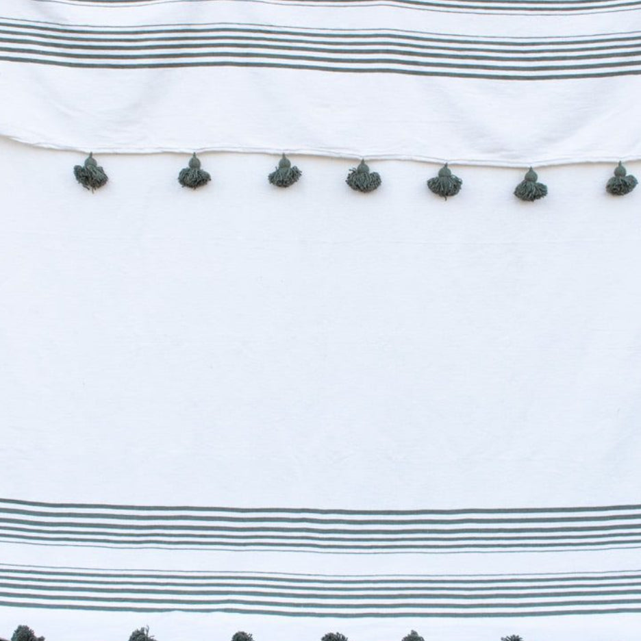 Manta blanca con lineas y pompones verdes