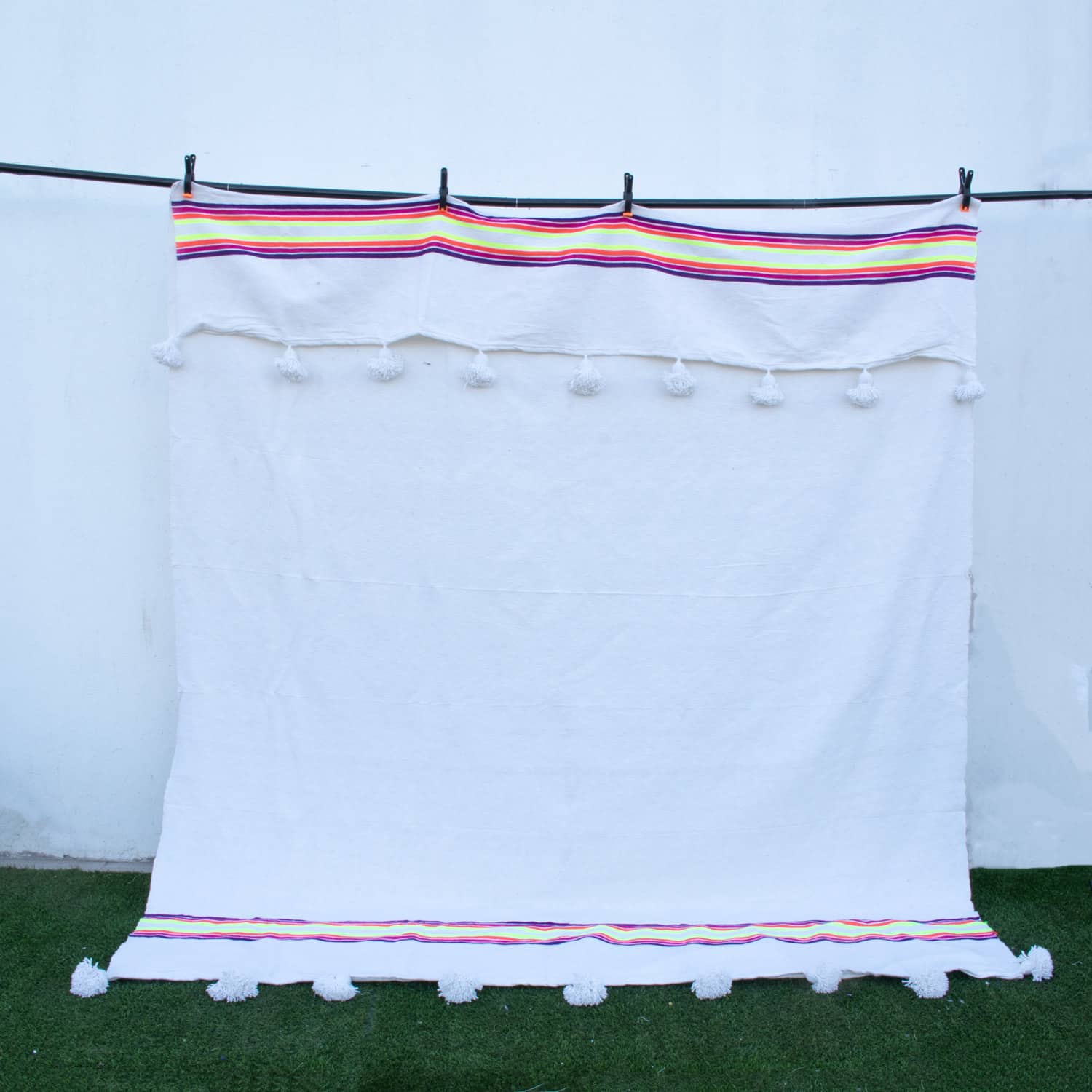 Manta Blanca con lineas de colores y pompones blancos
