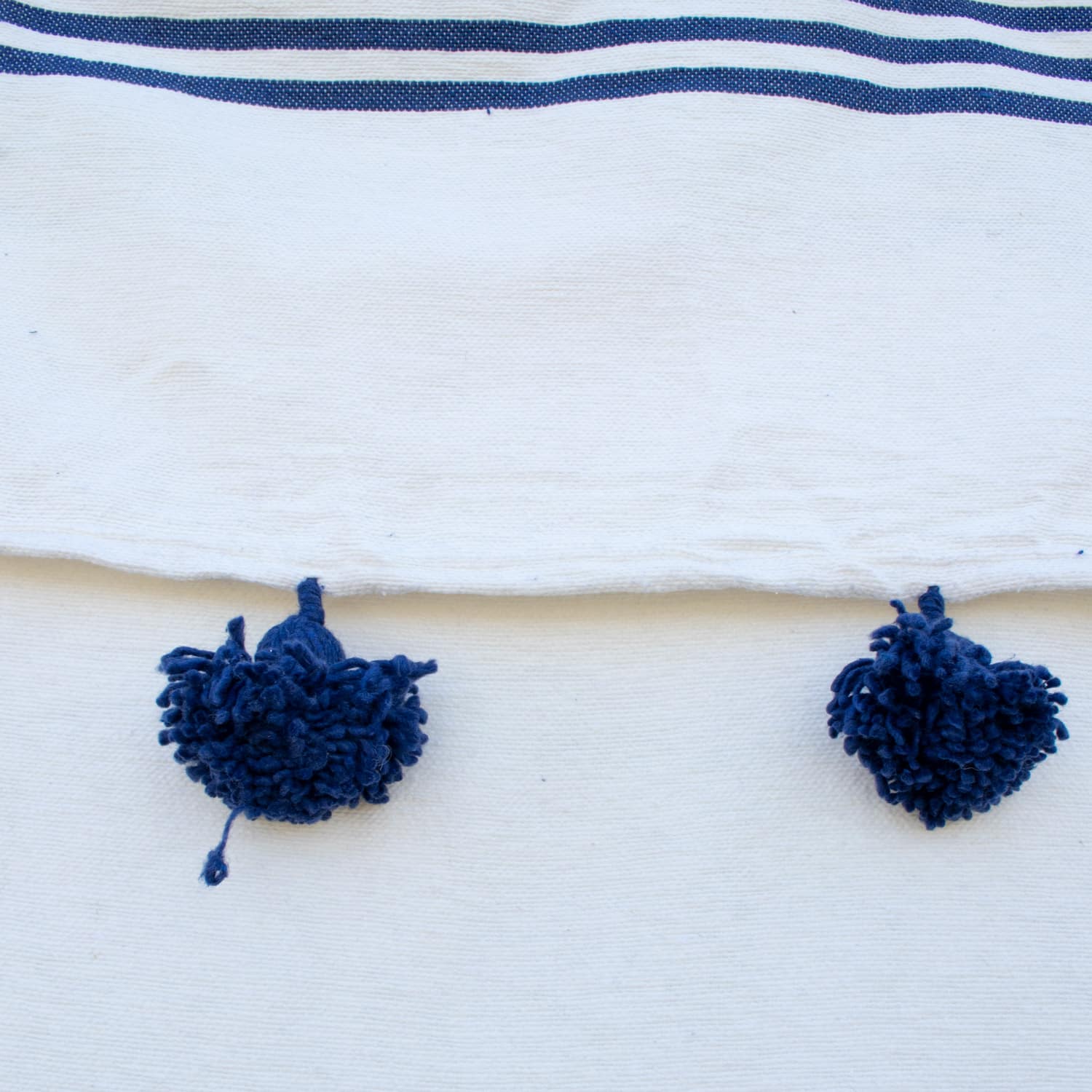 Manta Blanca con lineas azules y pompones azules