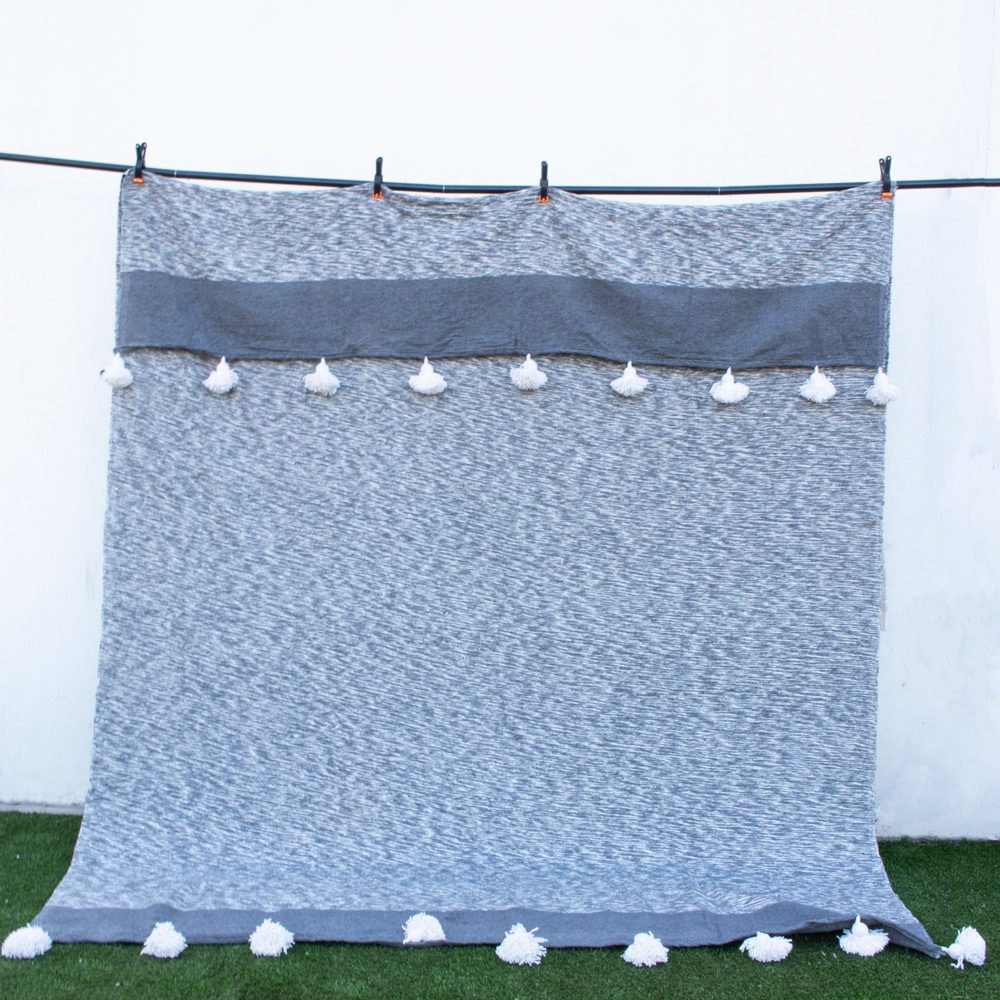 manta de algodon gris y blanca con pompones gris