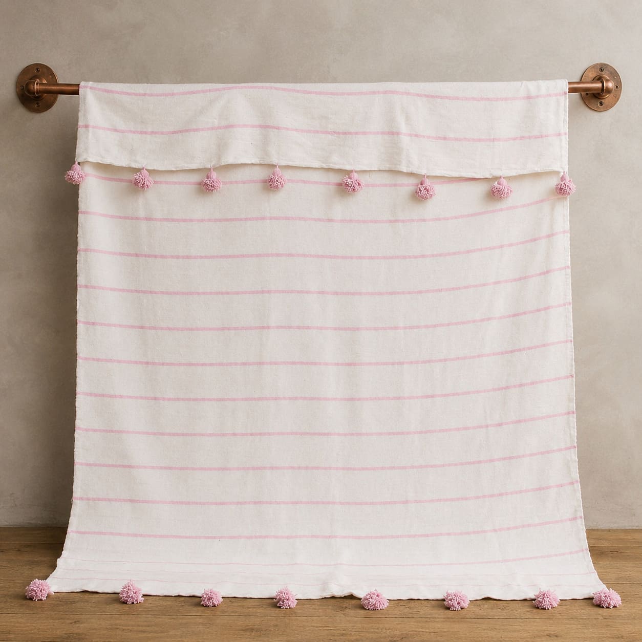 Manta blanca con lineas y pompones rosadas