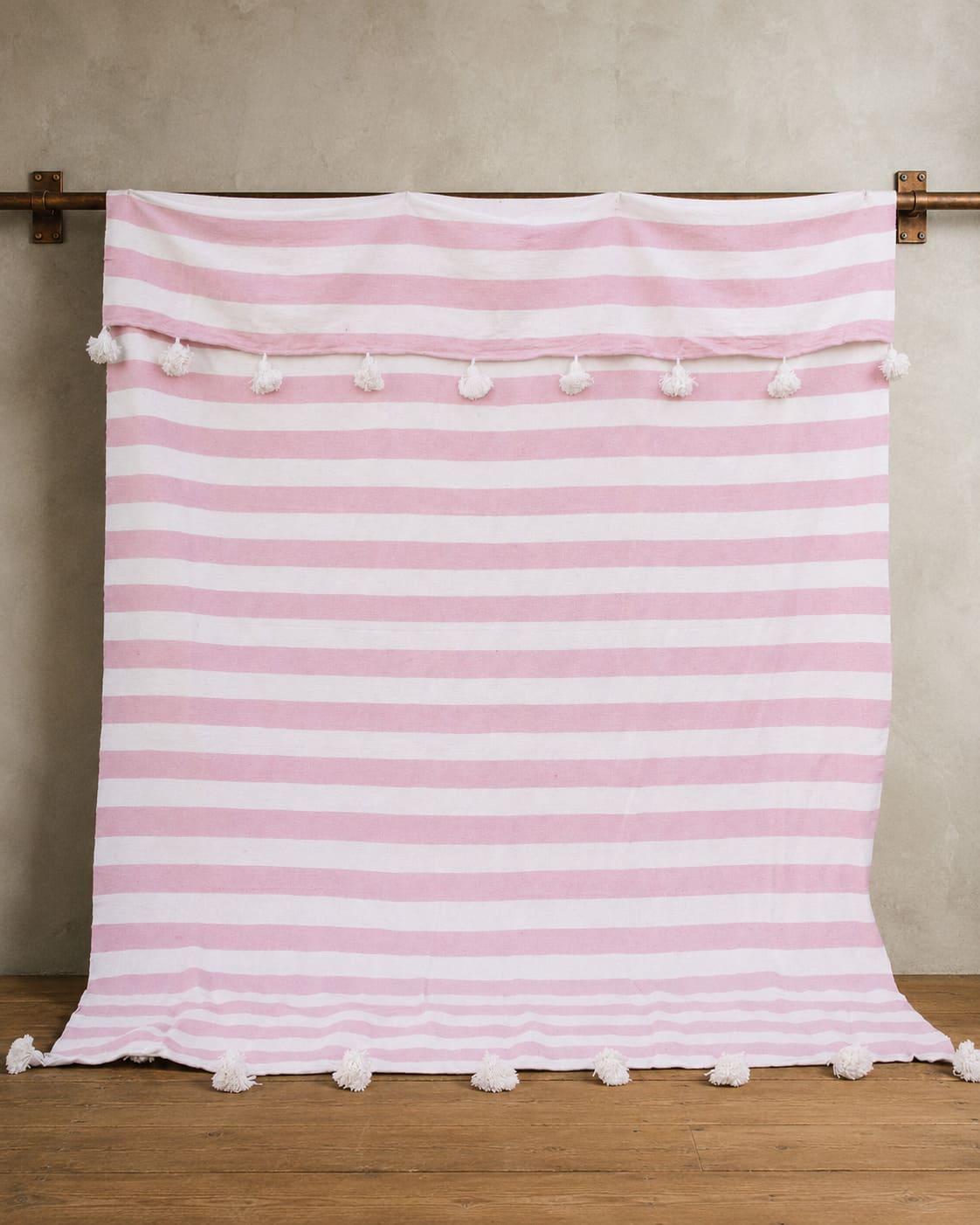 Manta blanca con lineas rosadas y pompones blancos